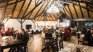 Ein geräumiges Restaurant mit hohen Decken und einem Strohdach, ausgestattet mit mehreren Esstischen und Stühlen.
