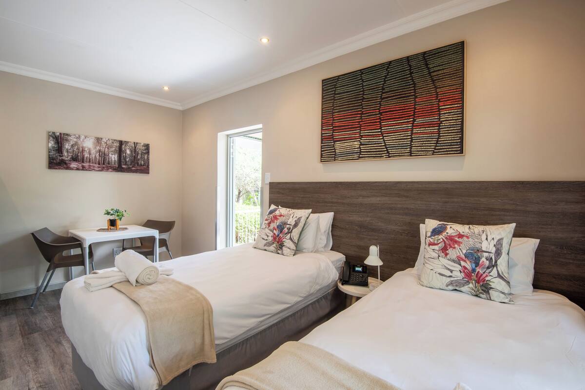 Une chambre d’hôtel avec deux lits, un bureau et une chaise.