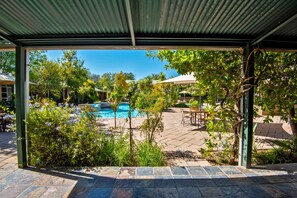 A pool area with a view of a swimming pool, surrounded by greenery and outdoor seating.
