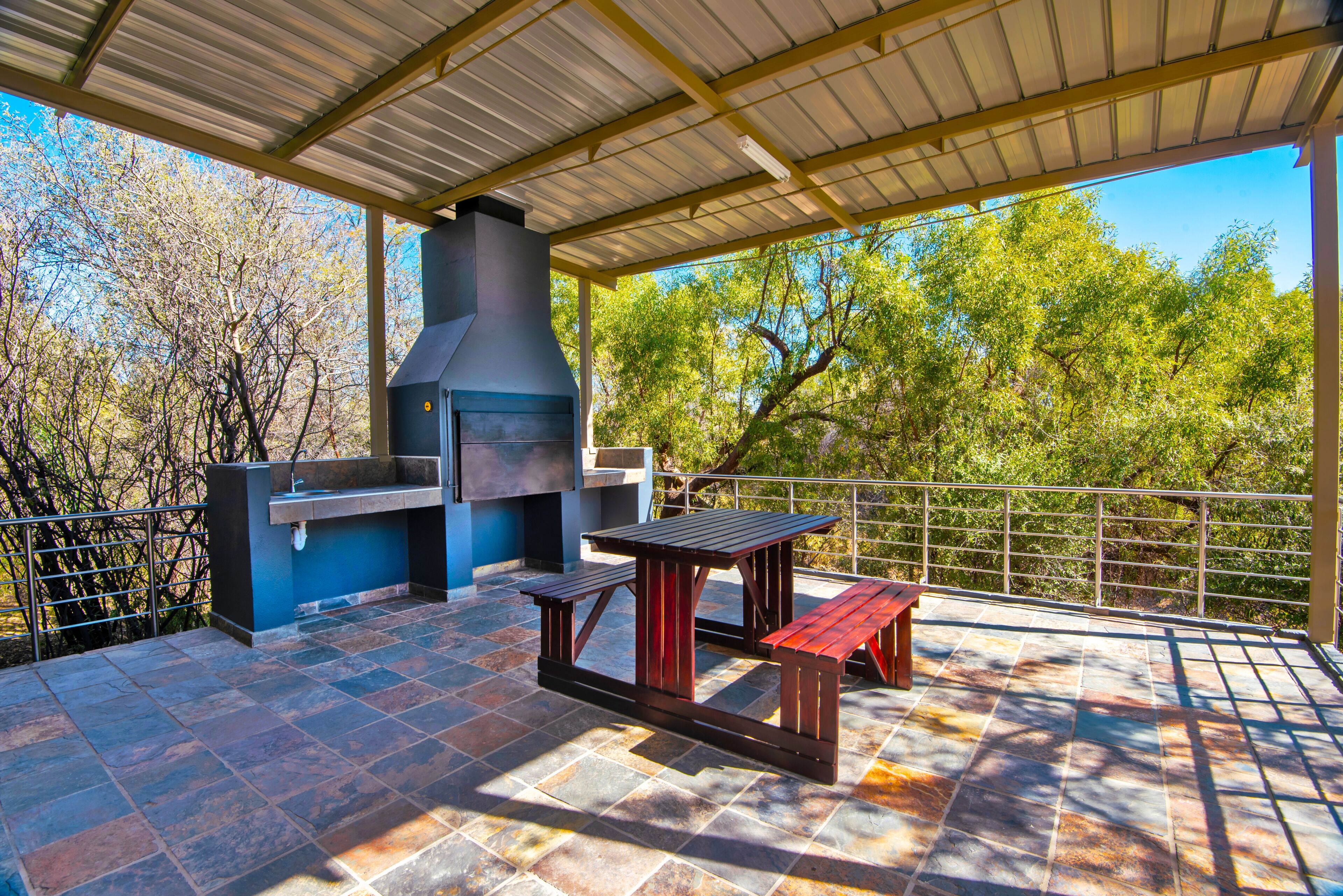 Eine Terrasse im Freien mit Grill, Tisch und Bänken.
