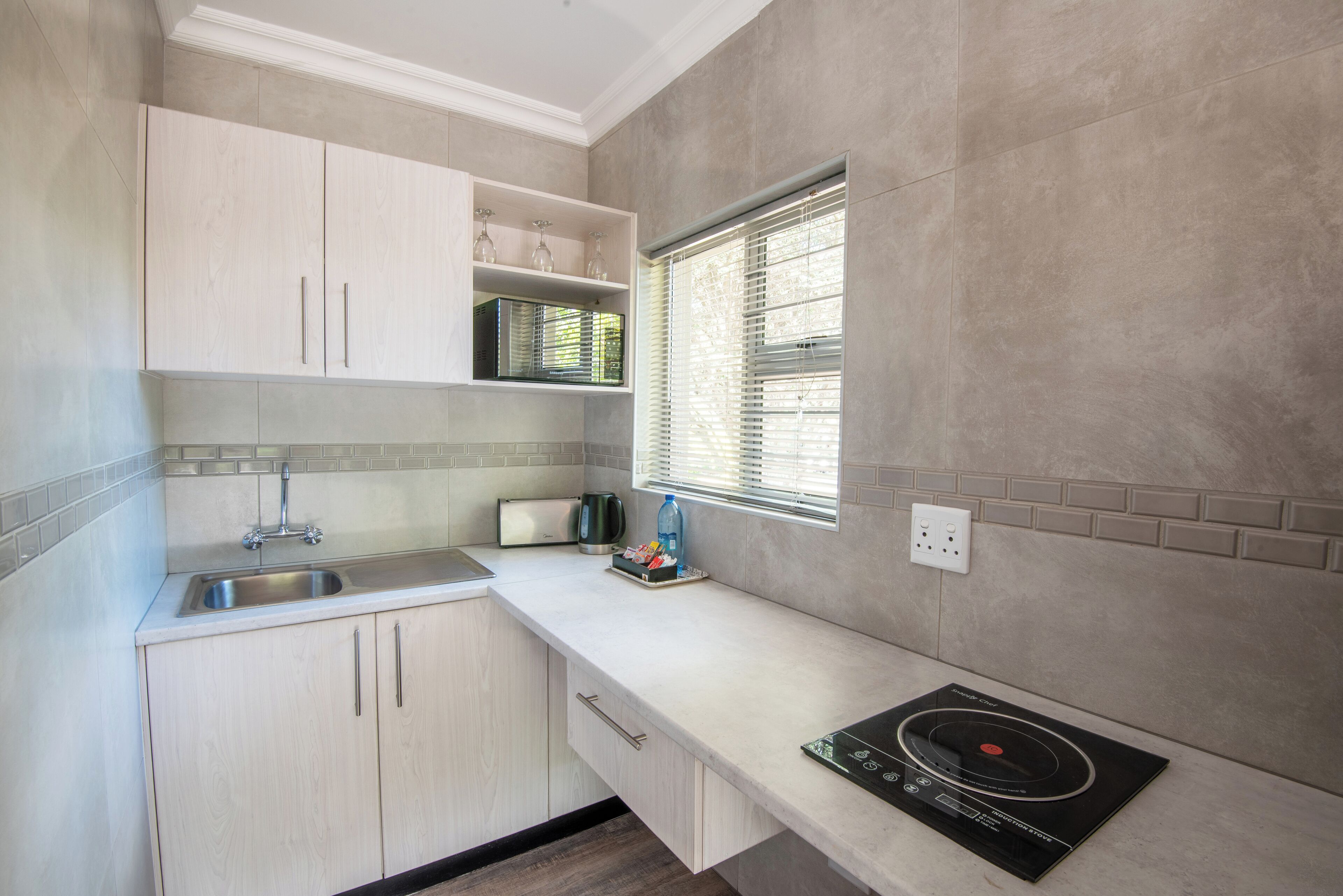 A modern kitchen with a built-in gas stove, a stainless steel sink, and light-colored cabinetry.