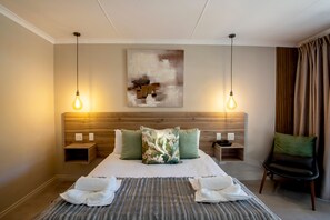 A hotel room with a large bed, two bedside tables, a chair, and a painting on the wall.