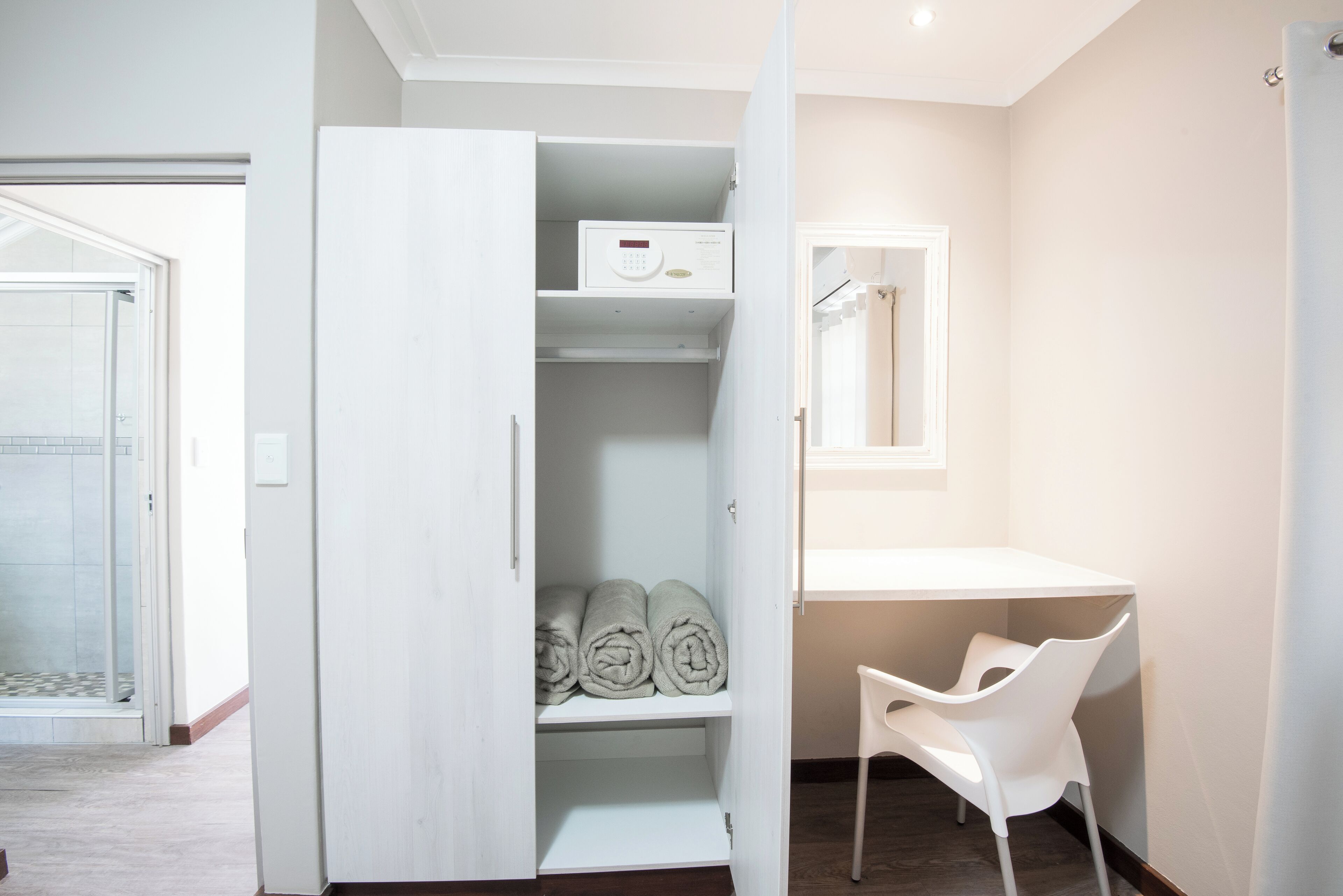 Un baño moderno con tocador blanco, perchero y zona de ducha.