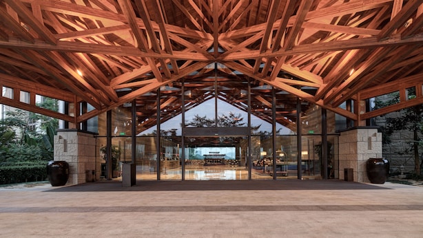 Un edificio moderno con estructura de techo de madera y amplia entrada de vidrio.