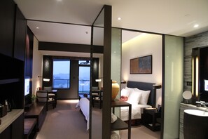 Una habitación de hotel moderna con una cama grande, mesitas de noche, un escritorio y vistas al exterior.