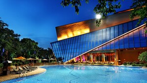 Un hotel moderno con una gran piscina, sillones de descanso y una fachada luminosa.