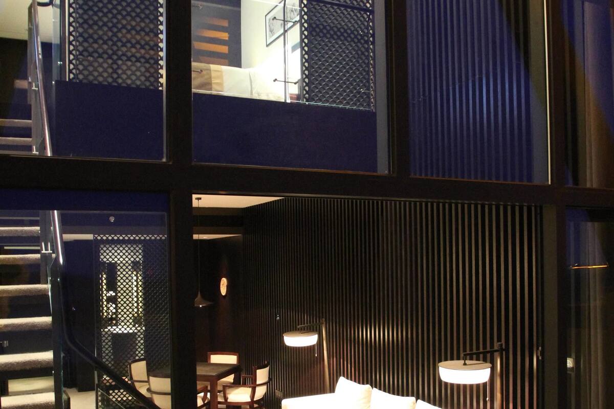 A modern interior with a staircase, a sofa set, and a dining area.