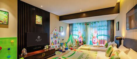 A children's room with a play area, two beds with animal-themed bedding, a television, and a desk with toys.