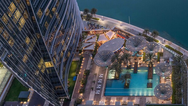 Luchtbeeld van een modern hotel met een zwembad, terras en uitzicht op zee.
