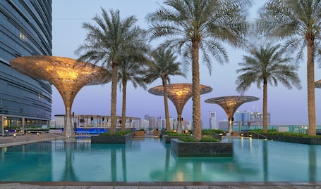 Una piscina al aire libre, sombrillas, sillones reclinables de piscina