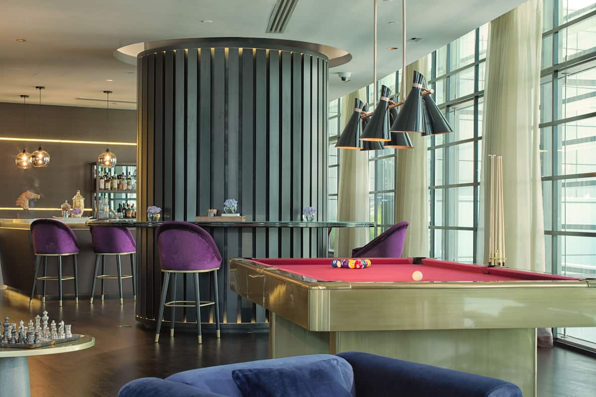 Un espace bar moderne avec une table de billard, des tabourets de bar et un comptoir.