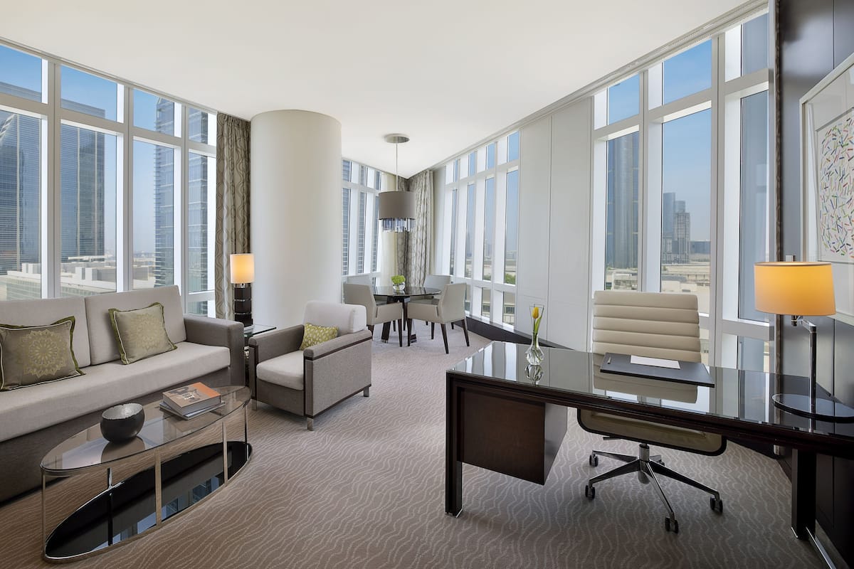 Une chambre d’hôtel moderne dotée d’une grande fenêtre, d’un canapé, d’un bureau et d’une chaise.