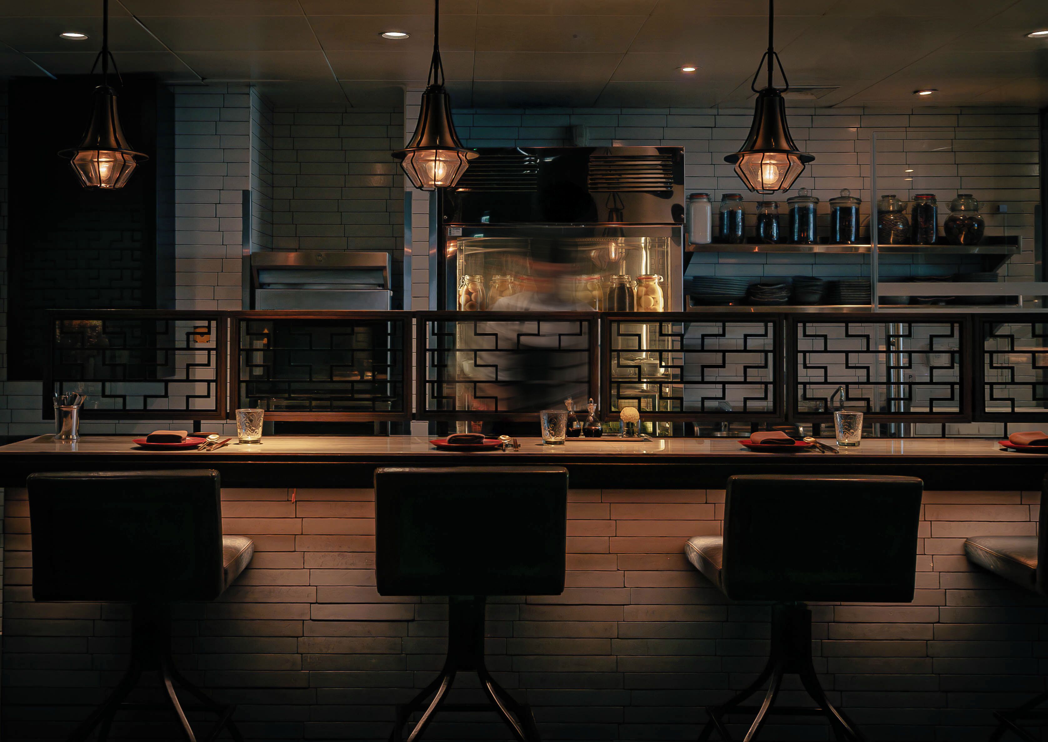 A modern kitchen with a brick backsplash, stainless steel appliances, and pendant lighting.