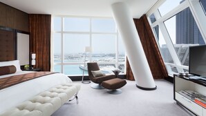 Een moderne hotelkamer met een groot bed, een bank, een stoel, een televisie en uitzicht op de stad.