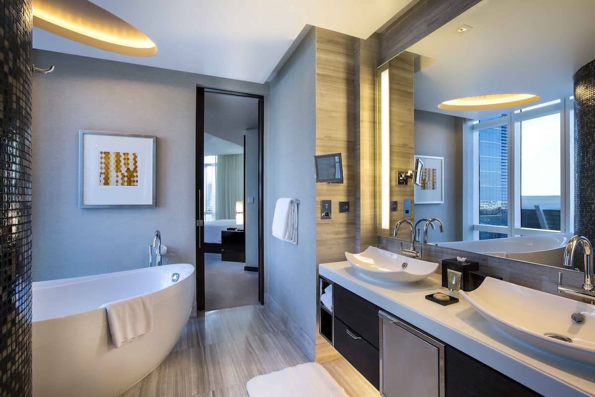 Une salle de bain moderne avec une baignoire, deux lavabos et un grand miroir.
