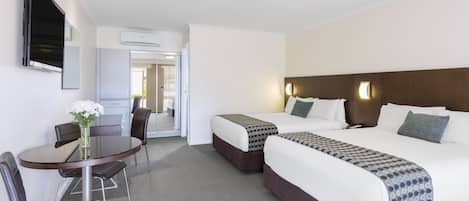 A hotel room with two beds, a desk, and a chair.