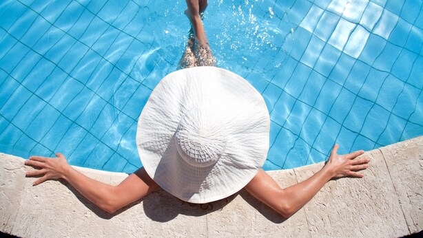 A person relaxing in a pool with a white hat, wearing swimwear, and holding onto the pool edge. - Mercure Wagga Wagga (Wagga Wagga)