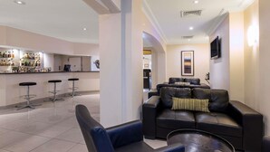 A modern living area with a sofa, chairs, a coffee table, and a bar area with stools. - Mercure Wagga Wagga (Wagga Wagga)