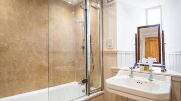 A bathroom with a glass-enclosed shower, a white sink, and a wooden-framed mirror.