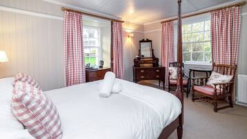 A bedroom with a four-poster bed, a dresser, a chair, and a window with curtains.