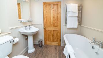 A bathroom with a wooden door, white sink, toilet, and bathtub.