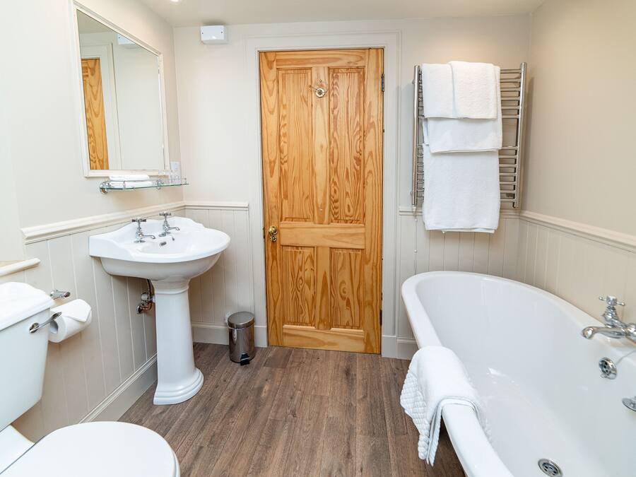 A bathroom with a wooden door, white sink, toilet, and bathtub.