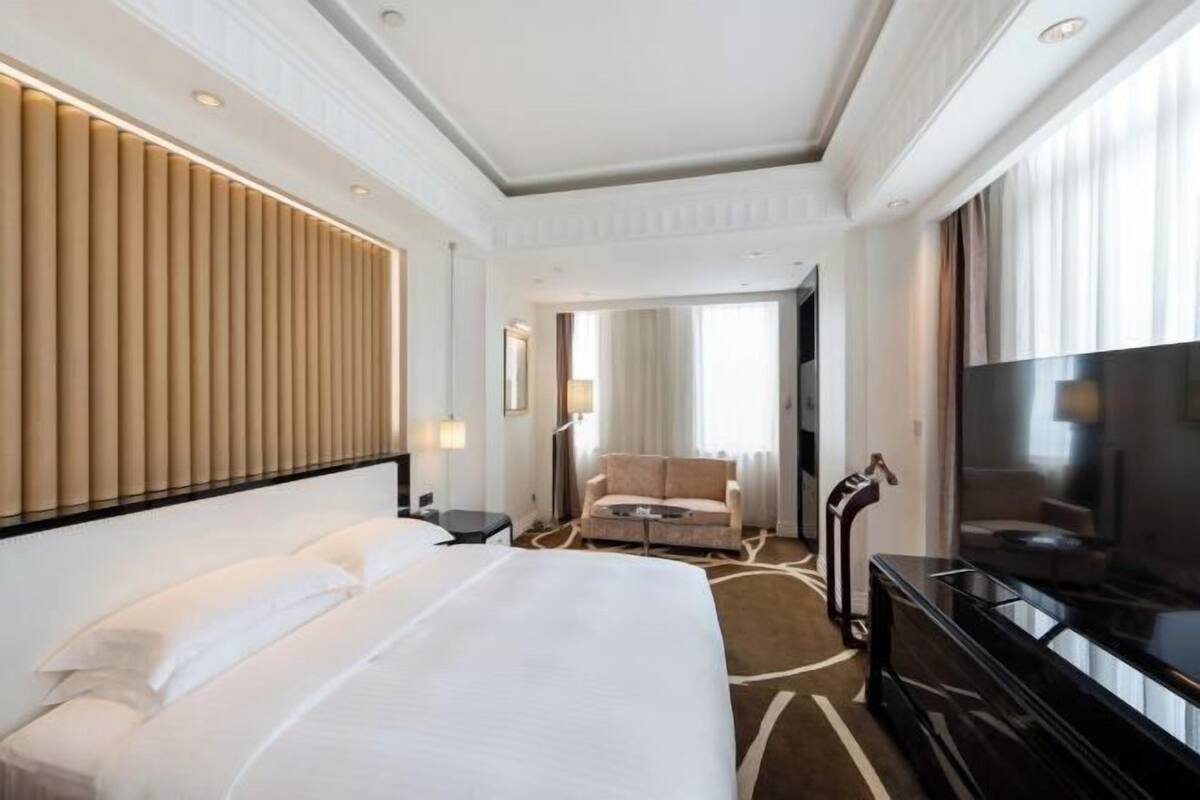 Quarto de hotel com uma cama grande, televisão, sofá e escrivaninha.