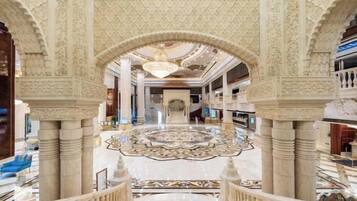 An ornate lobby with high ceilings, intricate ceiling patterns, and a central circular floor design.