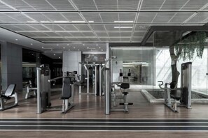 A modern gym with various exercise machines, a bench, and a mirrored wall. - Inspirock Hotel (Jiaxing)