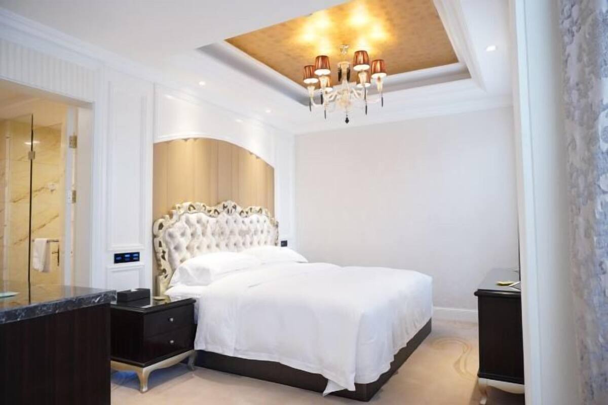 Quarto com uma cama grande, uma toucador com espelho e um candelabro.
