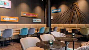 Ein stilvoller Lounge-Bereich mit Sitzgelegenheiten, Tischen und Wandbildern.