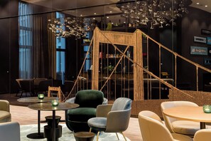 Un área de estar moderna con una escalera, asientos cómodos y una lámpara decorativa.