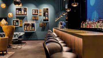 A bar area with a long counter, leather bar stools, and shelves with bottles.