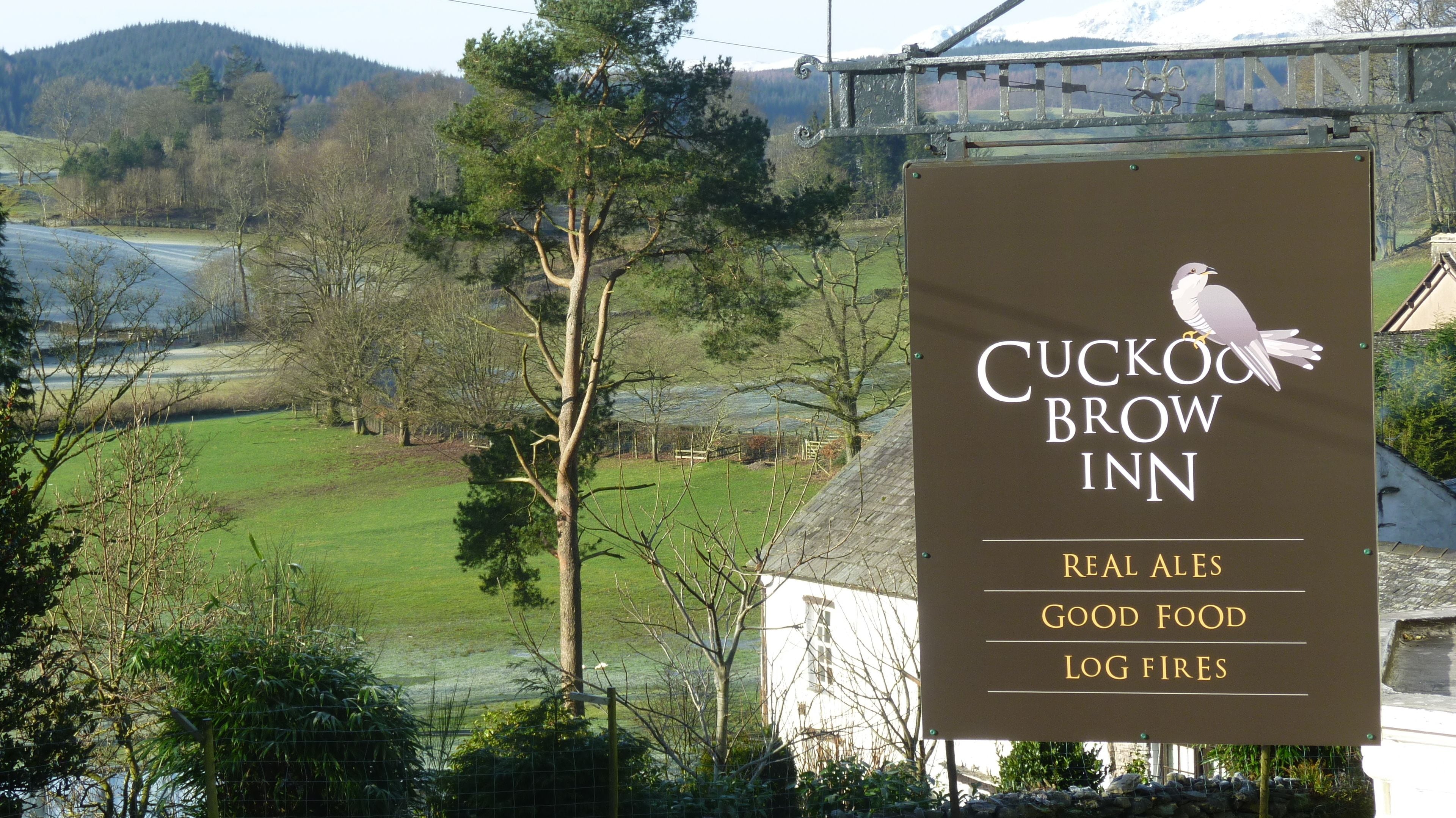 Señal del Cuckoo Brow Inn que anuncia cervezas artesanales, buena comida y chimeneas de leña.