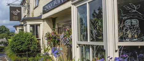 A traditional building with a sign reading "Cuckoo Brow Inn" and a shop window with a drawing of owls.
