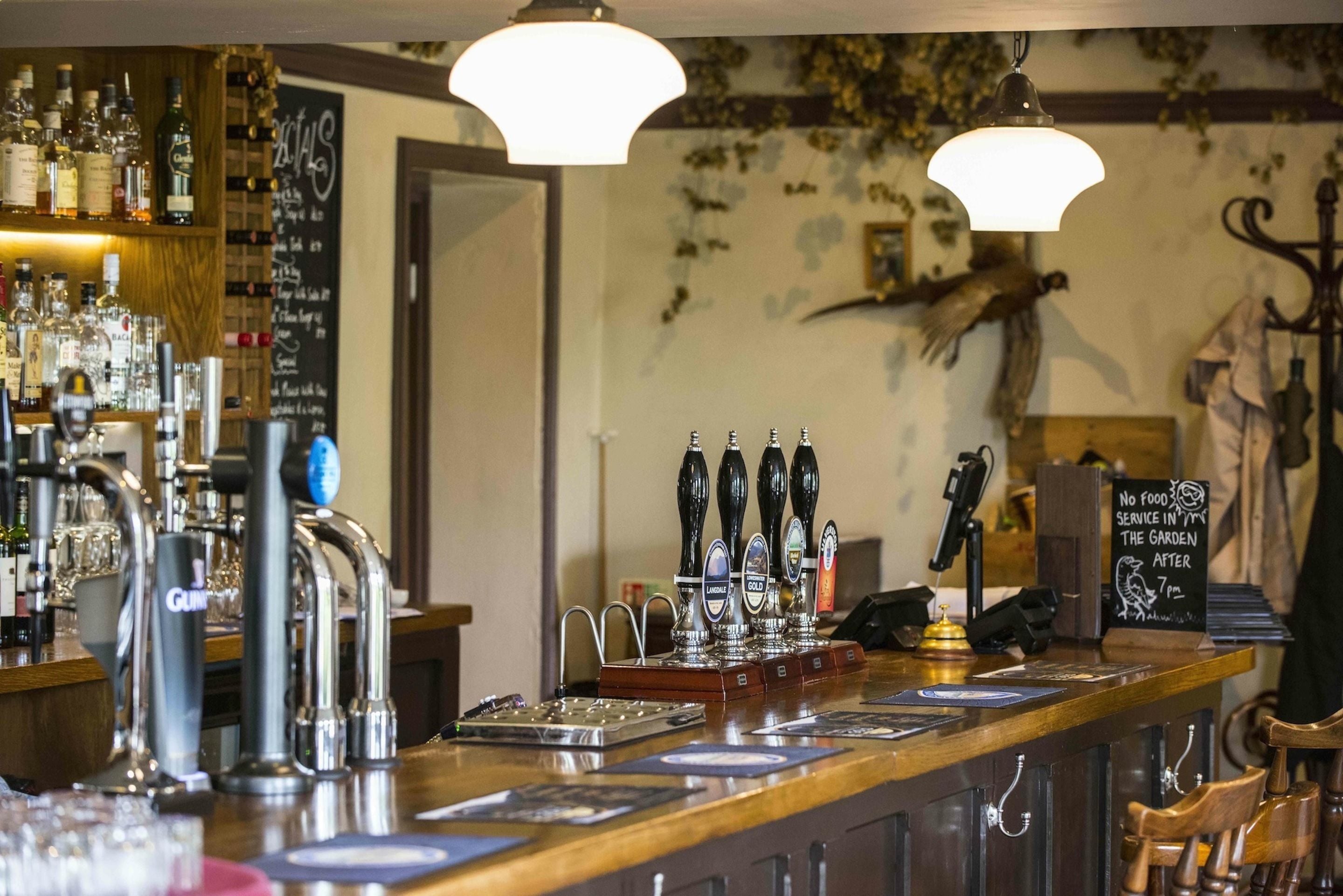 A bar area with multiple taps, a chalkboard menu, and a sign indicating no food service in the garden after a certain time.