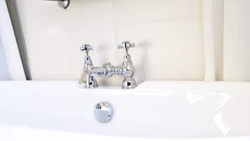 A white bathtub with chrome fixtures in a bathroom with tiled flooring.