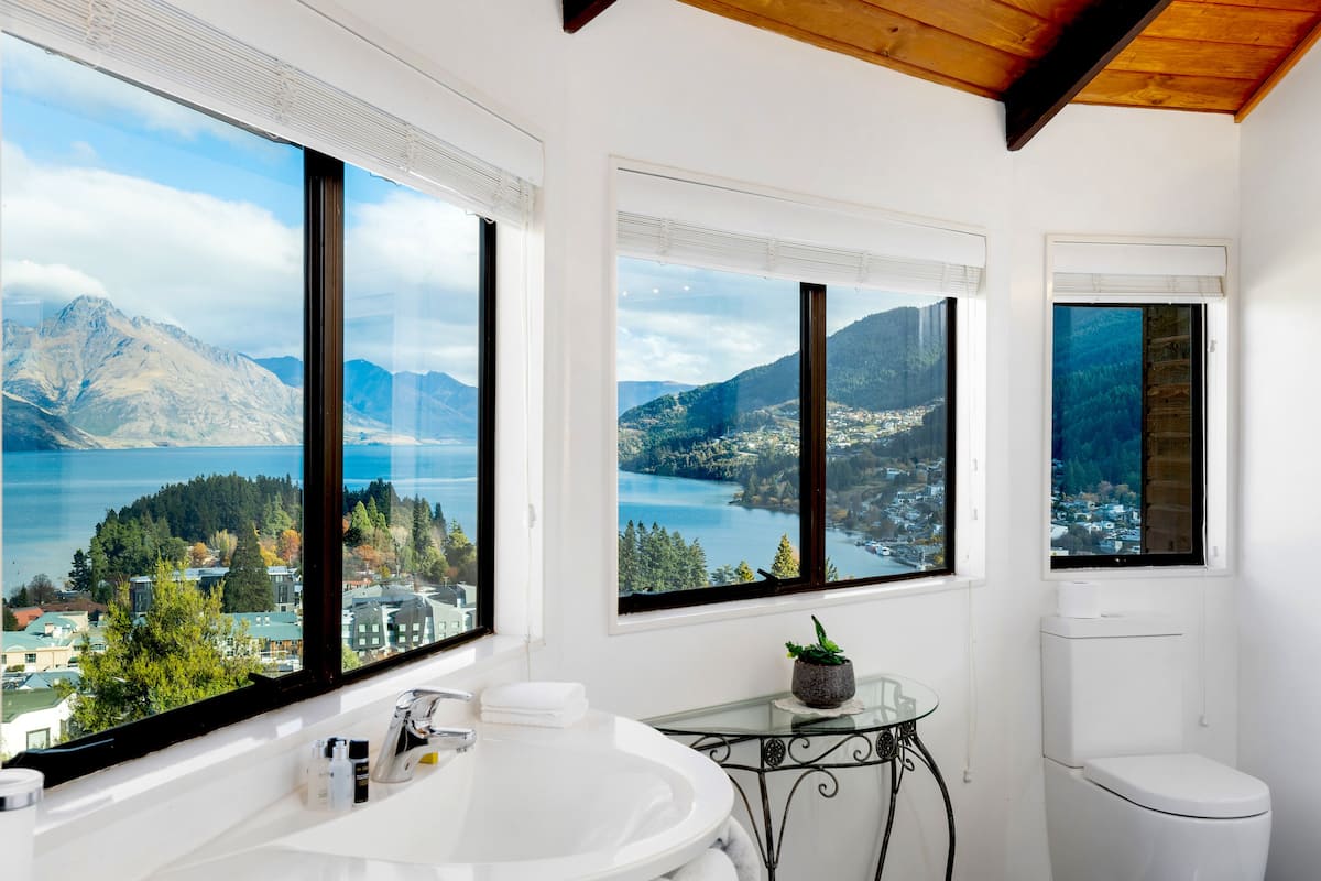 A bathroom with a large window offering a scenic view of mountains and a lake.