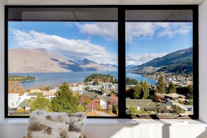 A view from a window overlooking a lake, mountains, and a town. - Balmoral Lodge (Queenstown)