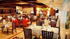 Un ristorante con diversi tavoli e sedie, un palco con un artista e un neon che recita 'Food Loft'.