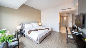 Una moderna camera d'albergo con un grande letto, comodini, una scrivania e una televisione a schermo piatto.