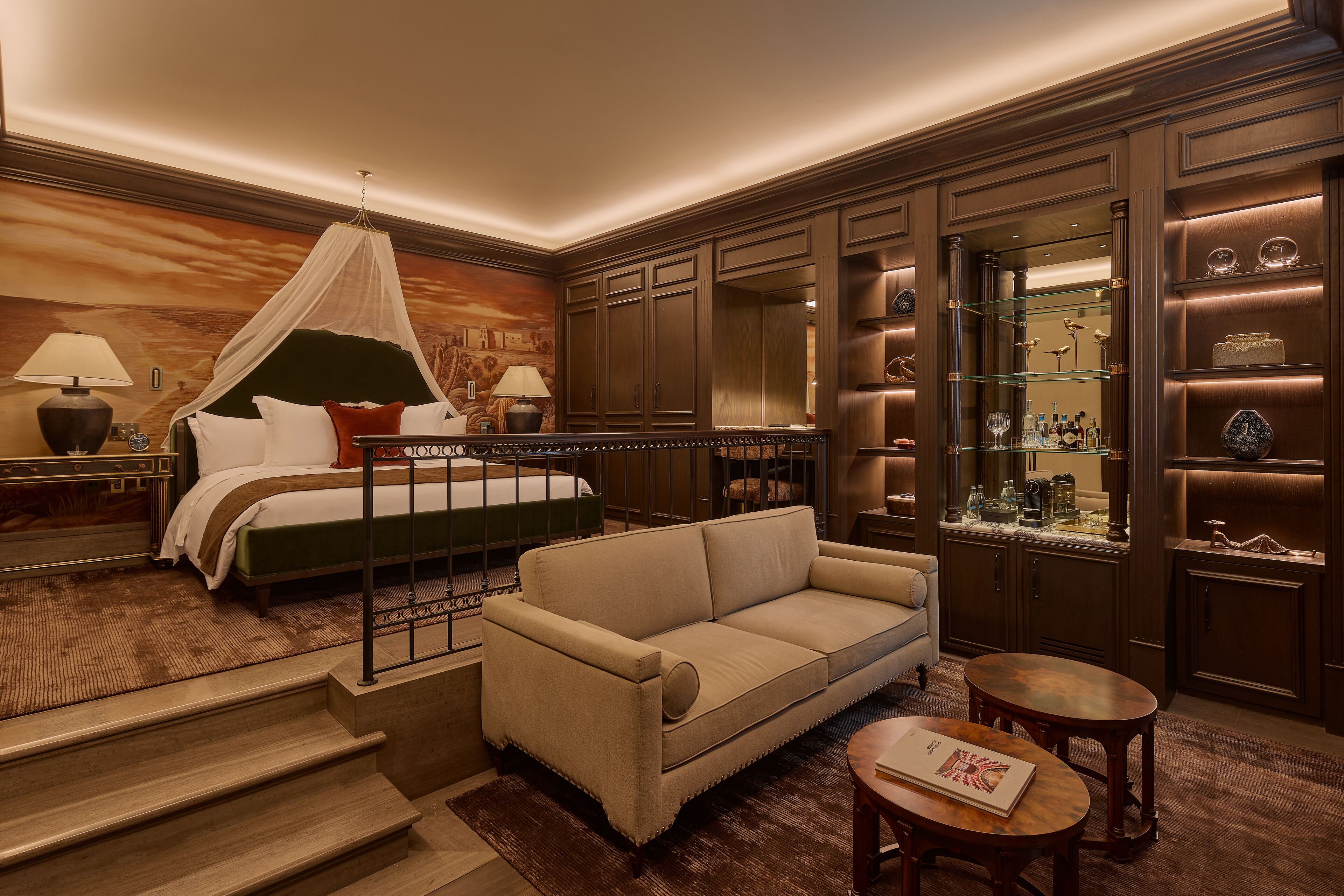 Quarto de hotel com cama, sofá, uma mesinha e espelho.