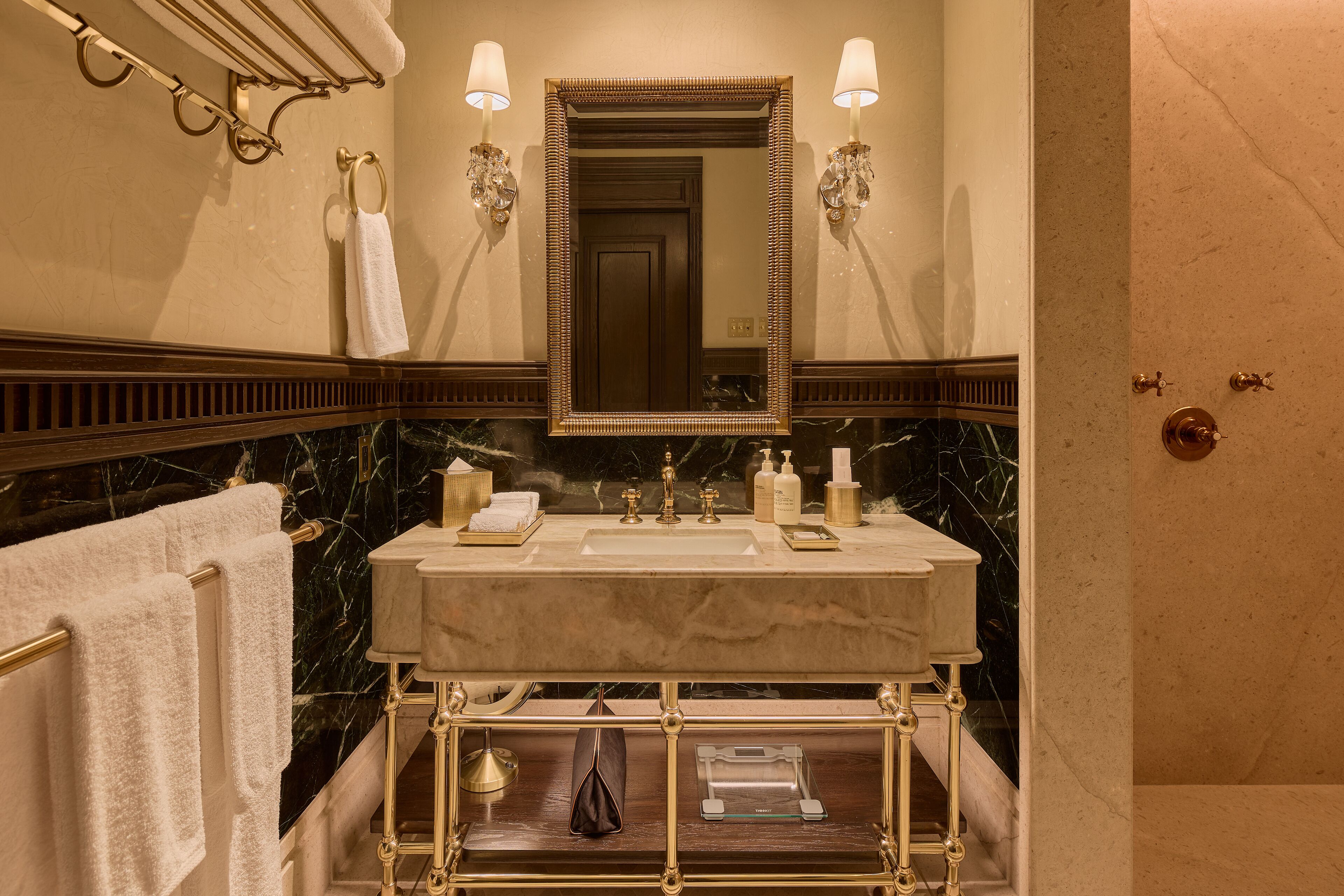 A bathroom with a marble sink, gold fixtures, and a large mirror.