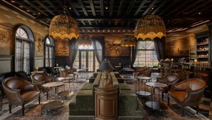 Un vestíbulo lujoso con sofás de cuero, mesas redondas y candelabros ornamentados.