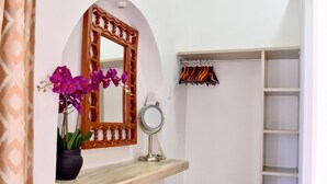 Un baño con tocador, espejo y estante con una orquídea en maceta.