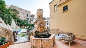 Una terraza en la azotea con una fuente de piedra, mobiliario exterior y vistas de la ciudad.