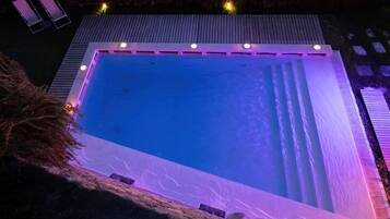 Ein rechteckiger Pool mit Holzterrasse und einer kleinen Sitzecke mit zwei Stühlen.