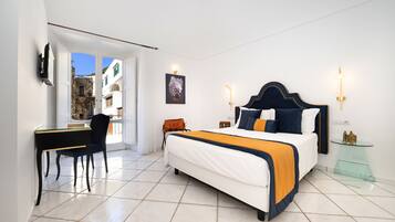 Ein Schlafzimmer mit Bett, Schreibtisch und Stuhl. Ein Fenster bietet Blick auf Gebäude.