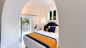 Un dormitorio con cama, mesita de noche, ventana con cortinas y vista a zonas verdes.