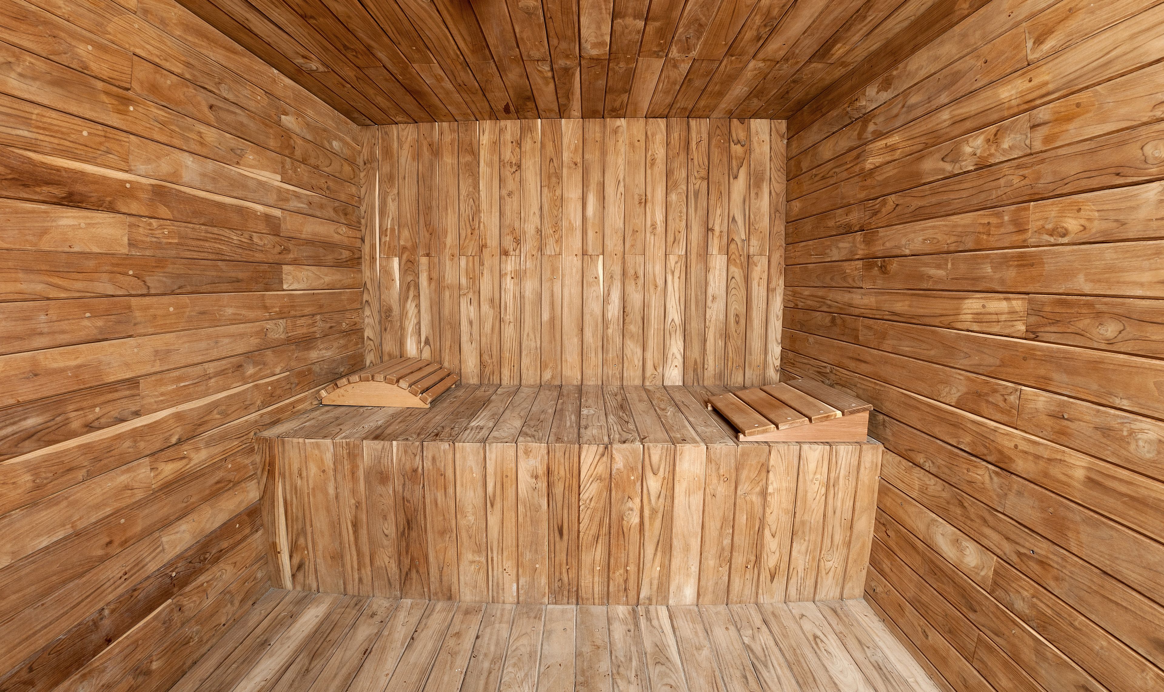 Una sauna de madera con bancos y suelo inclinado.
